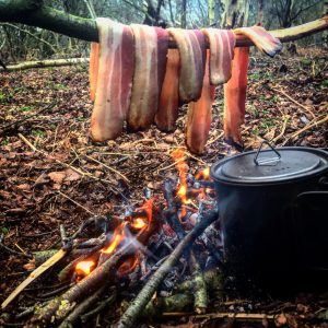 Bacon cooking over open fire.